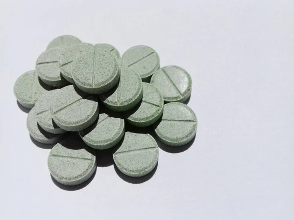 Växtbaserade tabletter av grå-grön färg på en vit bakgrund. Hälsovård. Medicinska konceptet. Medicinering intag. Kopiera utrymme — Stockfoto