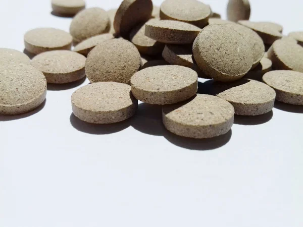 Close-up de pílulas de ervas marrons em um fundo branco. Saúde. Conceito médico. Ingestão de medicamentos. Espaço de cópia — Fotografia de Stock