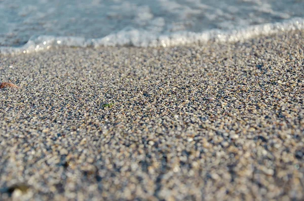 Primo piano della spiaggia sabbiosa con morbide onde in arrivo. Focus selettivo — Foto Stock