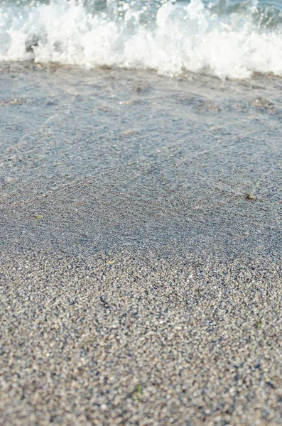 Primo piano della spiaggia sabbiosa con morbide onde in arrivo. Focus selettivo — Foto Stock