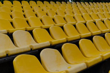 Stadyumda boş plastik sarı sandalyeler sıralar. Açık havada