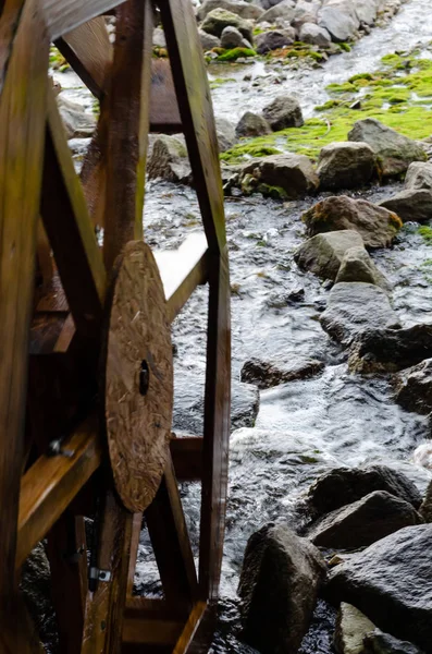 Wooden grist mill water wheel turning with the flow of water. Closeup
