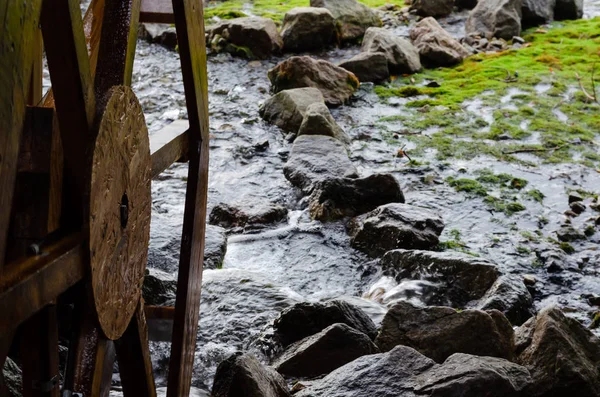 Wooden grist mill water wheel turning with the flow of water. Closeup