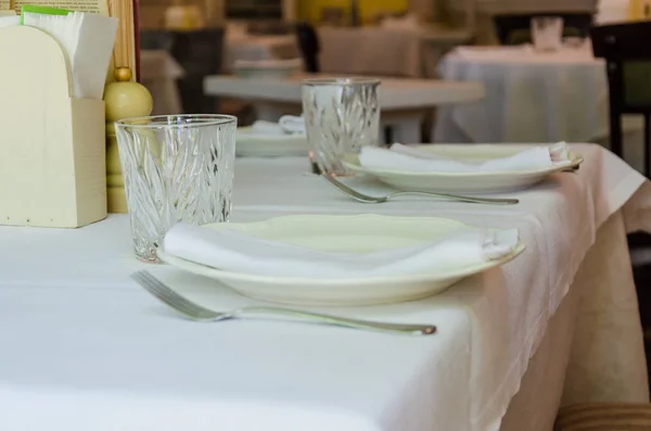 Configuração da mesa. Interior do restaurante. Limpar pratos, copos e talheres em uma toalha de mesa branca. Preparação para o serviço de hóspedes — Fotografia de Stock