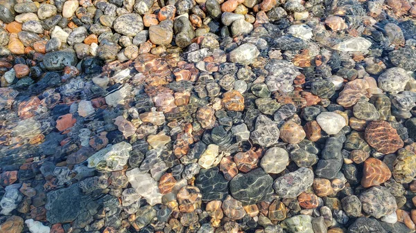 Pebble Beach som bakgrund. Lugnt koncept. Pebbles genom klart vatten — Stockfoto