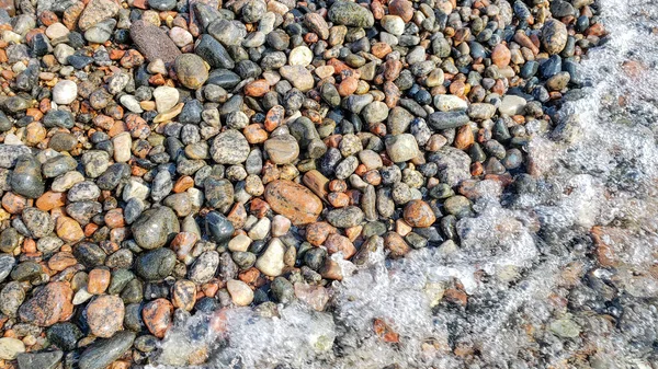 Praia de seixos como fundo. Concepção calma. Fechar-se de pedras multicoloridas molhadas — Fotografia de Stock