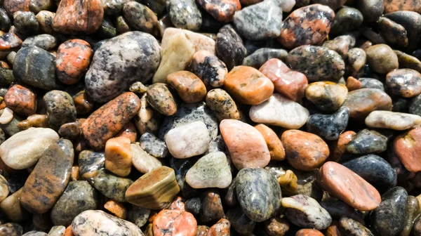 Spiaggia di ghiaia come sfondo. Concetto tranquillo. Primo piano di pietre multicolori bagnate — Foto Stock