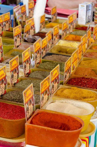 Containers with colorful spices and herbs in the market. Spice name plates — Stock Photo, Image
