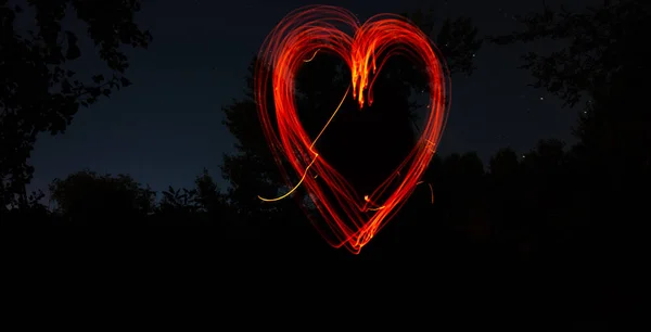 Karanlık bir arka plan daki ateşin çektiği kalp. Siyah bir gece arka plan üzerinde kırmızı kalp. Aşk, romantik ve festival konsepti — Stok fotoğraf