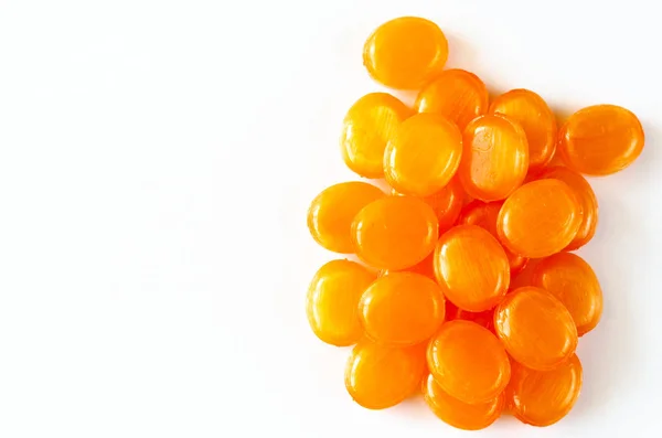 Primer plano de caramelos de frutas chupando duro sobre un fondo blanco. Un montón de caramelos naranjas. Copiar espacio. Vista superior — Foto de Stock