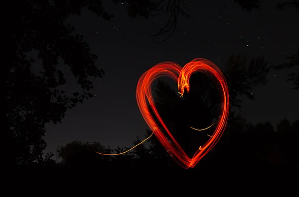 Heart drawn by fire on a dark background. Red heart on a black night background. Love, romantic and festival concept