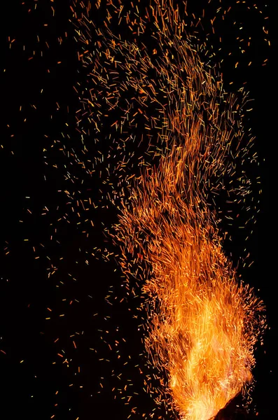 Siyah bir arka plan üzerinde yanan kırmızı kıvılcımlar uçan ateş Ateşi. Ateşli turuncu parlayan parçacıklar gece gökyüzünde uçup gitti. Güzel alev closeup