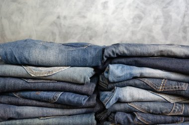 Dikkatsizce gri bir arka plan üzerinde iki kazık kot katlanmış. Farklı renklerde kot yakın çekim. Jeans doku veya denim arka plan. Kopyalama alanı