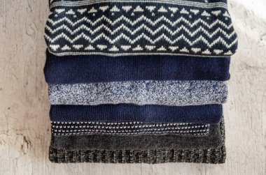 Gri arka plan üzerinde katlanmış sıcak örme erkek kazak yığını. Closeup. Seçici odaklama