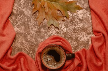 Sonbahar kompozisyonu. Portakal yün atkı ve meşe yapraklarına sarılmış bir fincan kahve. Sıcaklık, konfor ve rahatlık kavramı. Kopya alanı. Üst te. Düz yatıyordu