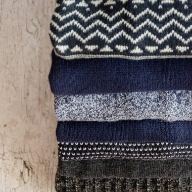 Gri arka plan üzerinde katlanmış sıcak örme erkek kazak yığını. Closeup