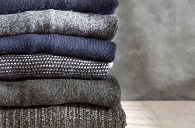 Gri arka plan üzerinde katlanmış sıcak örme erkek kazak yığını. Closeup. Kopyalama alanı