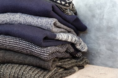 Gri arka plan üzerinde katlanmış sıcak örme erkek kazak yığını. Closeup. Kopyalama alanı