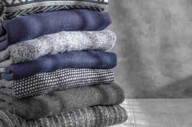 Gri arka plan üzerinde katlanmış sıcak örme erkek kazak yığını. Closeup. Kopyalama alanı