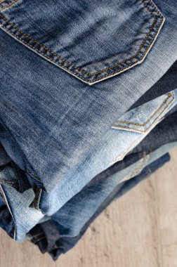 Ahşap arka plan üzerinde dikkatsizce katlanmış kot yığını. Farklı renklerde kot yakın çekim. Jeans doku veya denim arka plan. Kopya alanı. Seçici odaklama