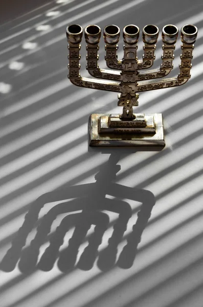 Traditional silver jewish menorah on a white background with stripes of shadow from the blinds — Stock Photo, Image