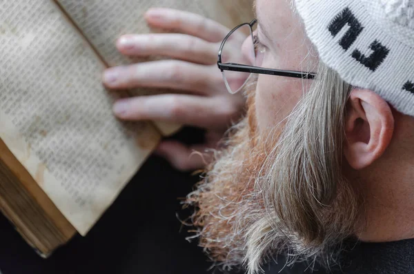 Ein hasidischer Jude liest siddur. Orthodoxer Jude mit rotem Bart und mit Tempo in weißem Ballen, der betet. Nahaufnahme — Stockfoto
