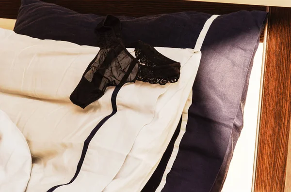 Culotte noire en dentelle pour femme sur un lit froissé. Matin après une nuit chaude. Concept de sexe rapide. Contexte du concept sexuel — Photo