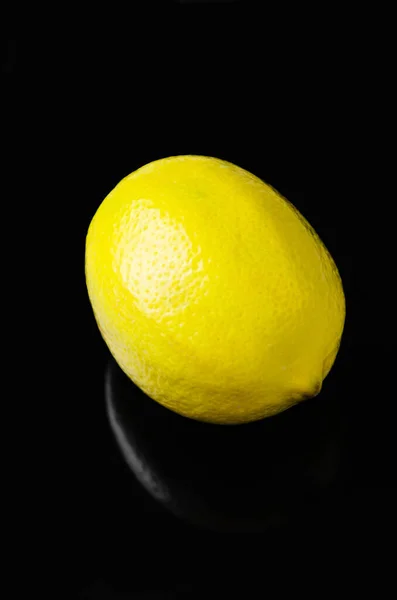 Pojedynczy świeży soczysty żółty cytryna na czarny błyszczący tło z odbicie. Przestrzeń kopiowania — Zdjęcie stockowe