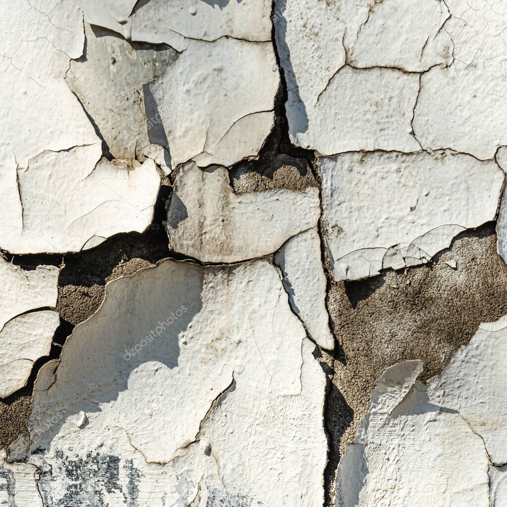 Old plaster wall surface. Abstract textured background. Deep cracks on a white wall. Closeup