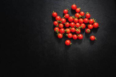 Siyah arka planda olgun kiraz domatesleri. Üst Manzara. Boşluğu kopyala