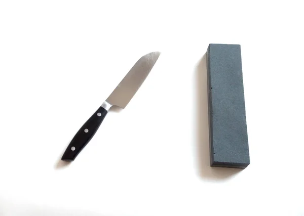 Cuchillo de cocina y piedra de afilar sobre fondo blanco- imagen — Foto de Stock