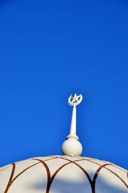 Mavi bulutların bir arka planına karşı bir caminin üstüne perdeli bir kuş