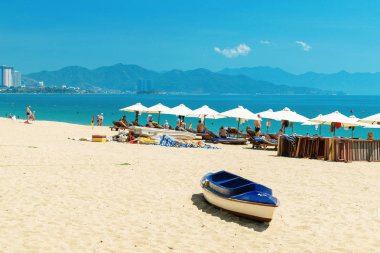 Nha Trang, Vietnam - 11 Nisan 2019: Okyanusa yakın kumlu plajda ve teknede bol şezlong ve şemsiye