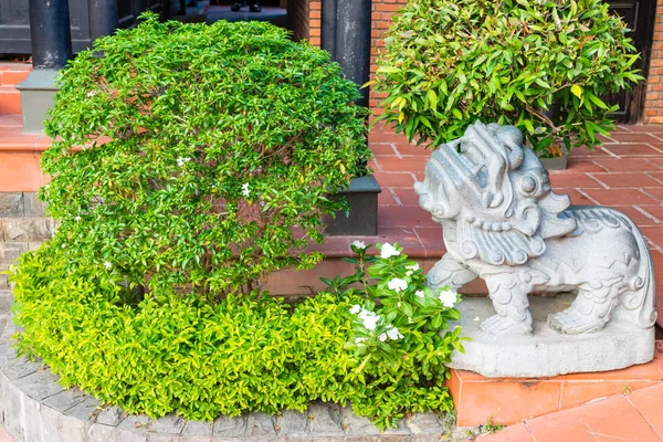 Arbusto verde con estatua de león de piedra — Foto de Stock