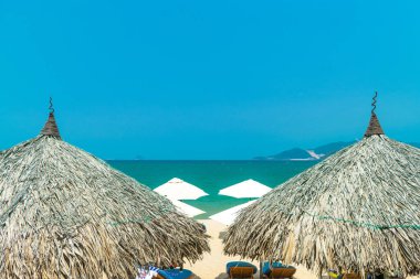 Güney Çin Denizi yakınlarındaki plajda şemsiye saman çatıları