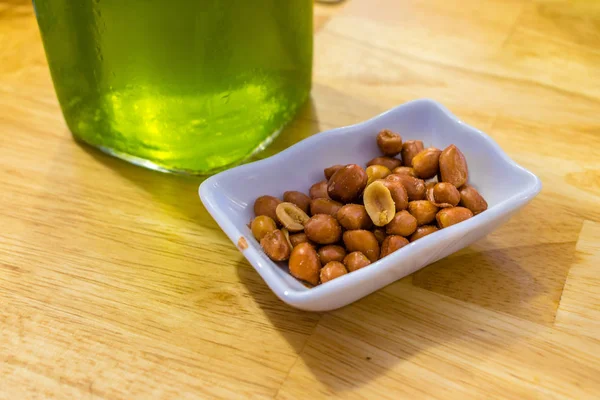 Bir masada yeşil bira yakın bir tabakta tuzlu kızarmış fıstık