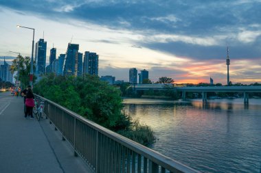 Viyana'da gün batımında Tuna yakınlarındaki köprüden gökdelenlere ve kuleye manzara