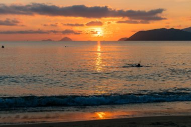 Kontrast bulutlar ile renkli şafakta denizde su üzerinde güneş ışığı nın izi