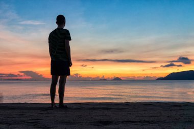 Okyanus üzerinde inanılmaz gökyüzü ile renkli bir gün doğumunda sahilde insan siluetleri
