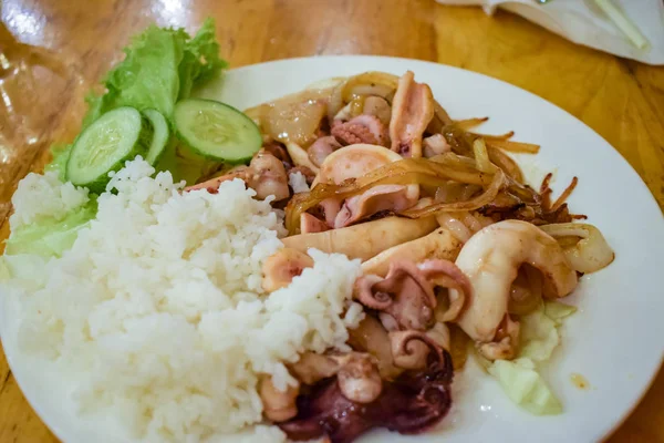 Жареные морепродукты с вареным рисом и зеленым огурцом на белой тарелке — стоковое фото