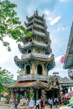 Dalat, Vietnam - 15 Nisan 2019: Turistler bulutlu gökyüzüne karşı yüksek pagoda ve bir ağaç dalı altında yürümek