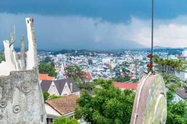 Yeşil ağaçlar ve arka planda binaların çatıları ile çatıda Paslı paratoner