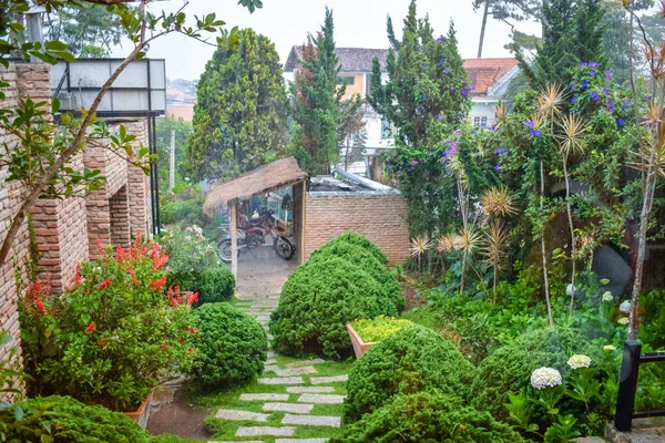 Lluvia tropical en el patio con arbustos verdes y una motocicleta bajo un dosel — Foto de Stock