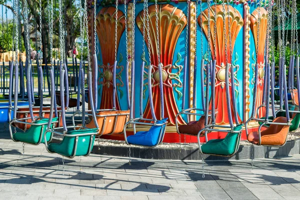 Colorful metal swings on chains in an amusement park without people