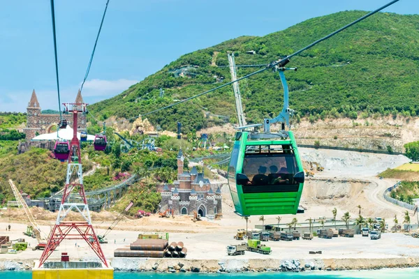 People in the cable car cabin to the amusement park on green island with development on shore