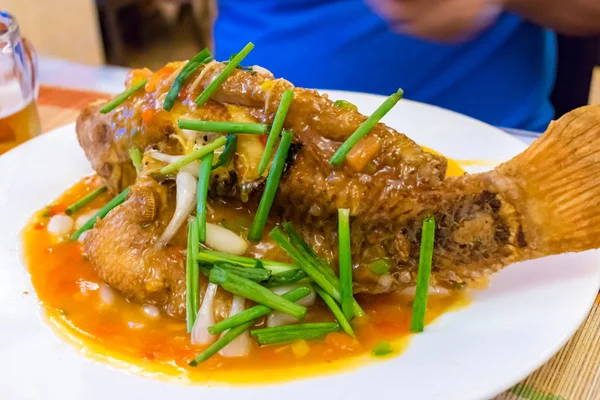 Stekt fisk i sås med grön lök på tallrik i restaurang — Stockfoto