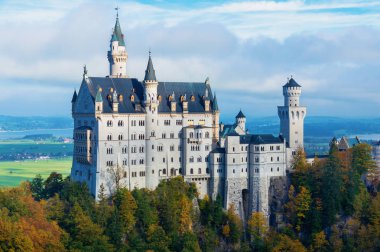 Arka planda bulutlu bir gökyüzü ile sonbaharda sabah güneşinde Neuschwanstein kale