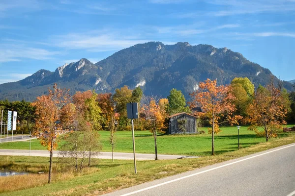 Straße in einem Dorf mit gelben Bäumen vor dem Hintergrund der Berge in den Alpen — Stockfoto