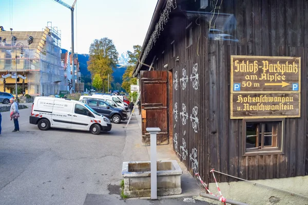 Schwangau, Niemcy-Oktober 09, 2018: drewniana stodoła i parking samochodowy z kierunkowskazu na ścianie — Zdjęcie stockowe