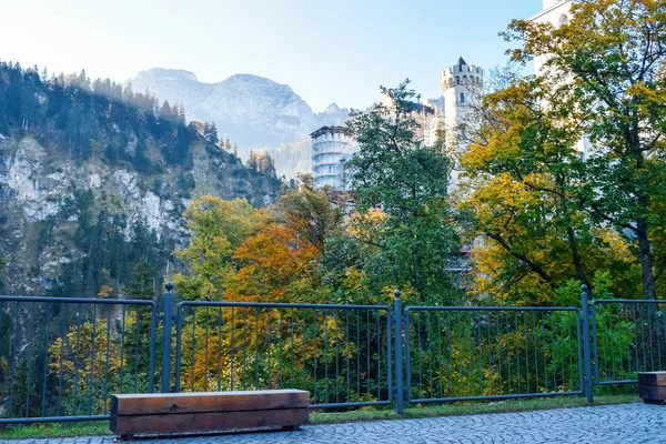 Banco y valla de metal con el castillo de Neuschwanstein sobre un fondo en las montañas de los Alpes —  Fotos de Stock